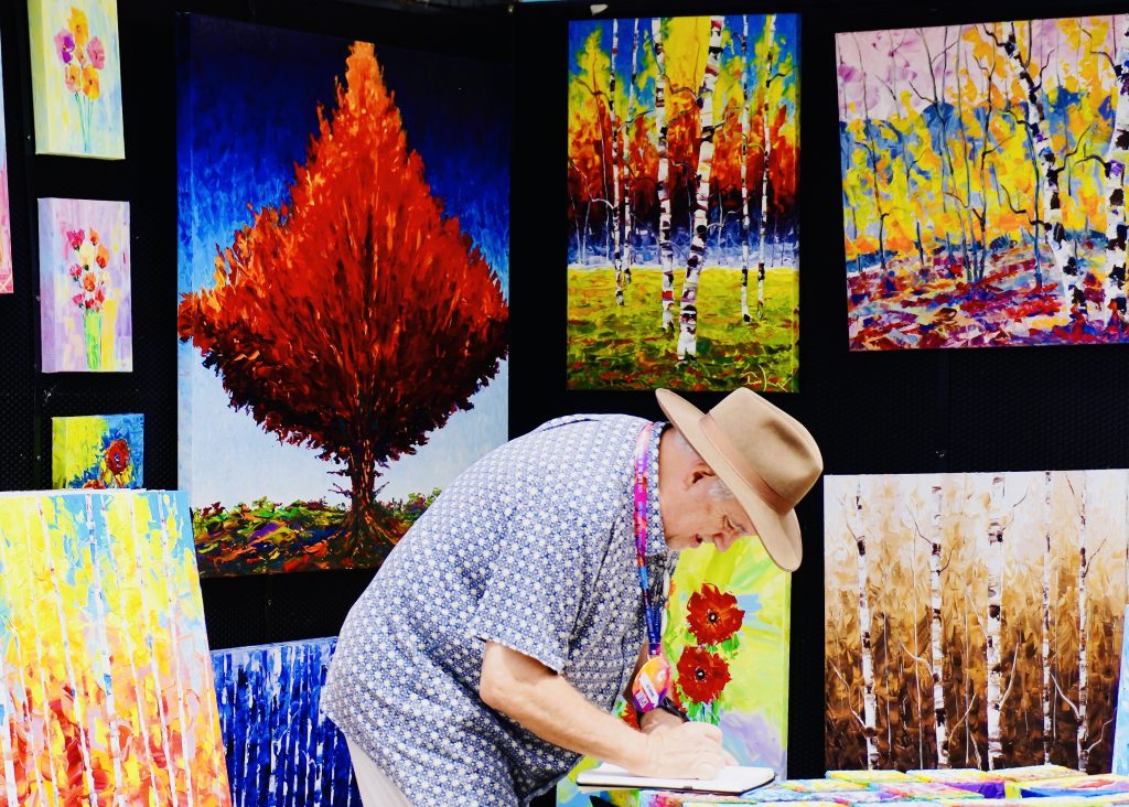 Tim Kenney finishes filling out paperwork after selling one of his paintings at the Festival of Arts in Oklahoma City. Photo and Video credit Karintha